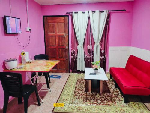 een woonkamer met een rode bank en een tafel bij Pink Homestay D'Perlis in Kangar