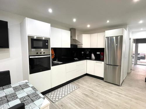 uma cozinha com armários brancos e um frigorífico de aço inoxidável em Beautiful Las Rosas em Arona