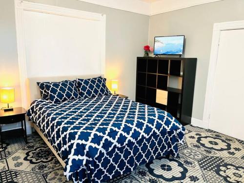 een slaapkamer met een blauw en wit bed en een televisie bij 3 bedrooms 2 stops to Manhattan in Long Island City