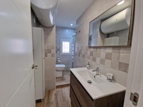 W łazience znajduje się umywalka, toaleta i lustro. w obiekcie Precioso apartamento centro Sevilla zona Nervión. w Sewilli