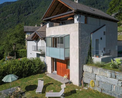 a house on a hill with chairs and an umbrella at Maison 4 soleil. Casa design luce e natura in Crodo