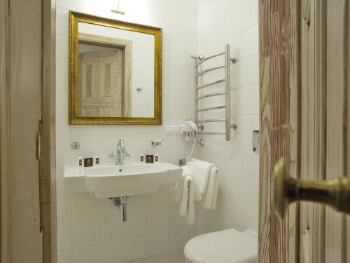 W łazience znajduje się umywalka, toaleta i lustro. w obiekcie George Hotel w Lwowie