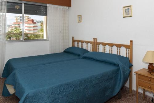 a bedroom with a bed with blue sheets and a window at Florazar 2, Vi-3-B in Faro de Cullera