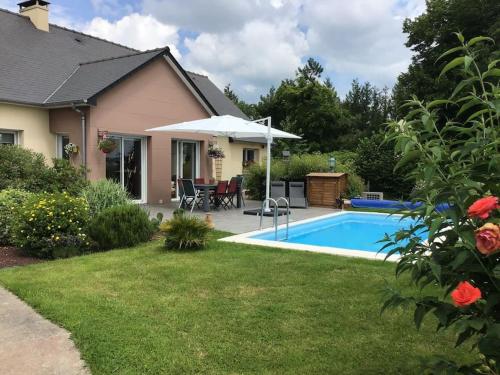 un patio trasero con piscina y una casa en Maudon Coeur de Baie, en Ponts