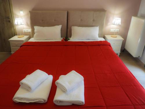 ein Schlafzimmer mit einem roten Bett mit zwei weißen Handtüchern darauf in der Unterkunft Stadium Sea Beach Apartment in Kissamos
