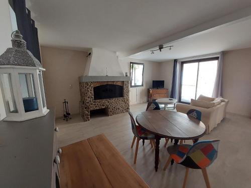 a living room with a table and a fireplace at Maison de Sao en pierres in Lablachère