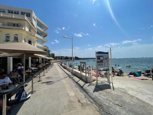 a beach with people sitting on the sand and the water at Centre de Juan les pins 100m plages Easy Check-in in Juan-les-Pins