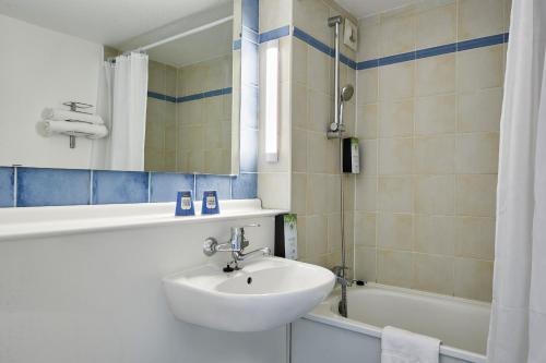 塔布的住宿－Kyriad Tarbes Bastillac，浴室配有盥洗盆、镜子和浴缸
