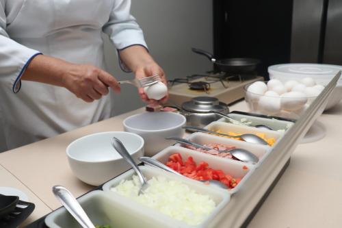 a person in a kitchen preparing food on a counter at Hotel Adrianópolis All Suites in Manaus