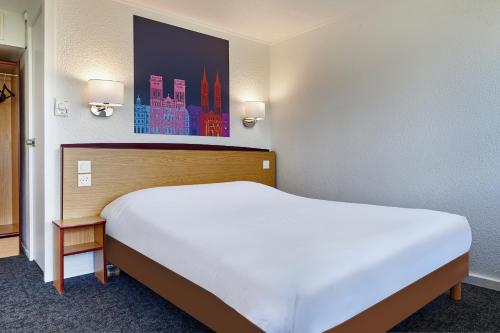 a large white bed in a hotel room at Kyriad Tarbes Bastillac in Tarbes