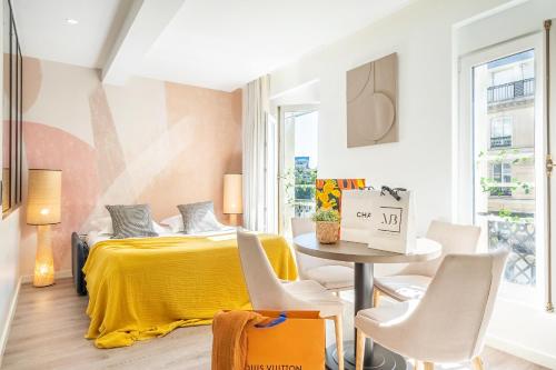 - une chambre avec un lit jaune, une table et des chaises dans l'établissement Yuna Les Halles - Serviced Apartments, à Paris