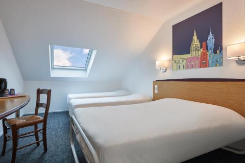 a hotel room with two beds and a table and a desk at Kyriad Tarbes Bastillac in Tarbes