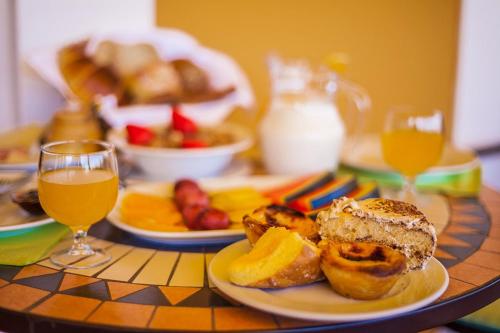 una mesa con un plato de comida y un vaso de jugo de naranja en Montinho De Ouro, en Luz