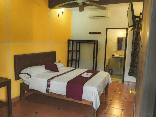 a bedroom with a bed in a room with yellow walls at Hotel Hacienda la Alborada in Tuxtla Gutiérrez