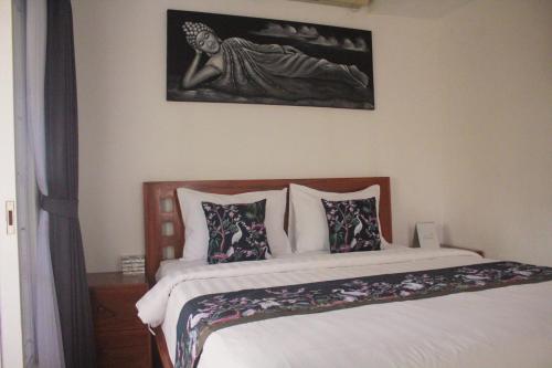 a bedroom with a bed with pillows and a painting on the wall at Summer Homestay Bali in Nusa Dua