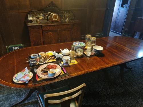 einem Holztisch mit Teller mit Lebensmitteln darauf in der Unterkunft Old Manor House in Shepperton