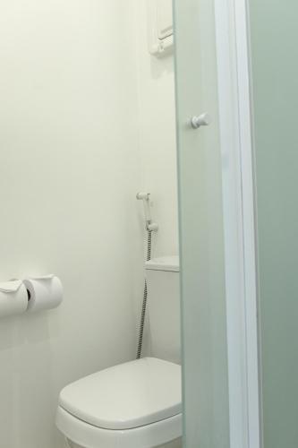 a white bathroom with a toilet and a roll of toilet paper at Express Vieiralves in Manaus