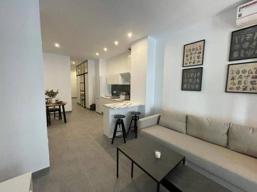 ein Wohnzimmer mit einem Sofa und einer Küche in der Unterkunft COMPLEJO PINTA18 AT1, AT2 y AT3 in Sevilla
