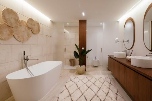 een badkamer met een bad, 2 wastafels en een spiegel bij Troya Regal Villa by CadenzaLux in Troia