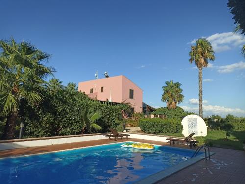 a swimming pool with two chairs and a house at Sicilian Paradise in Castelvetrano Selinunte