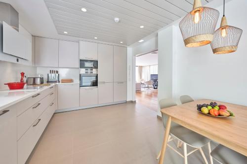 a kitchen with white cabinets and a wooden table at La Villa at The Cliff Bay - PortoBay in Funchal