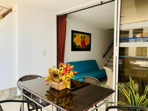 sala de estar con mesa y sofá azul en Santa Marta Apartamentos - Palanoa, en Santa Marta