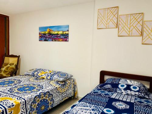 a bedroom with two beds and pictures on the wall at Santa Marta Apartamentos - Palanoa in Santa Marta