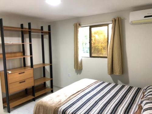 um quarto com uma cama, uma prateleira e uma janela em Apartamento aconchegante no Bessa em João Pessoa