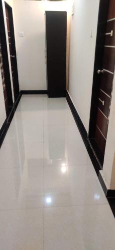 a hallway with a black door and a white floor at Diamond Cottage in Alibaug