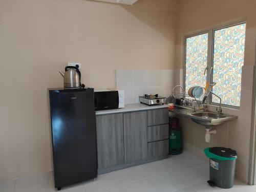 een keuken met een zwarte koelkast en een wastafel bij Sutra Damai Seaview in Kuantan
