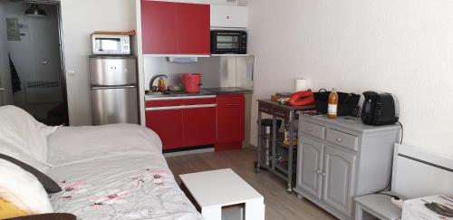 una pequeña cocina con armarios rojos y nevera. en appartement pendine 1 plein sud 53m2, en Puy-Saint-Vincent