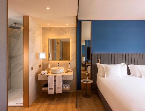 a bedroom with a bed and a bathroom with a sink at Barceló Tanger in Tangier