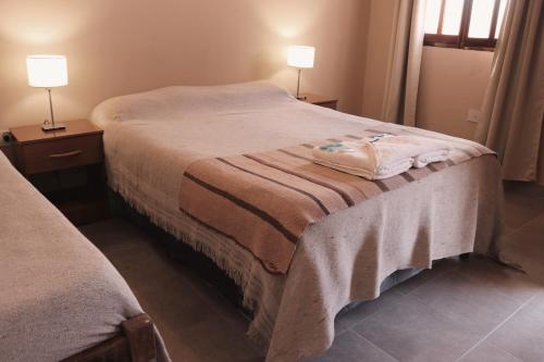 łóżko w pokoju z dwoma lampami na stołach w obiekcie El Caucillar w mieście Iruya