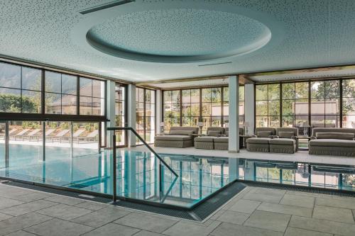 a swimming pool in a building with furniture and windows at Hotel Bräu in Zell am Ziller