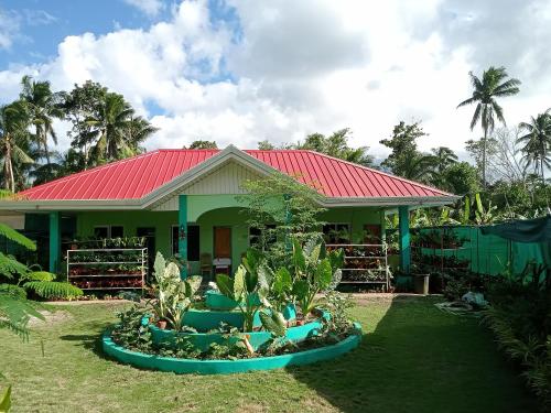 BARRIL GREEN HOMESTAY في Batuan: منزل بسقف احمر وبعض النباتات