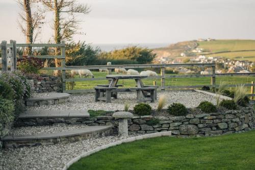 a picnic table in a garden with a stone wall at Sea View in Poundstock