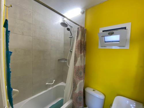 a bathroom with a shower and a yellow wall at The Condo Palace in Agia Marina in Agia Marina