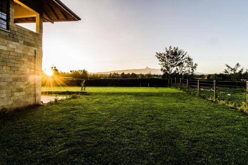 a person standing in a field with the sun setting at The Landing Nanyuki - One Bedroom Guest house in Nanyuki