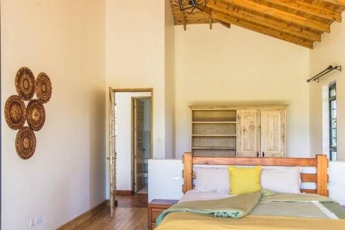 a bedroom with a wooden bed with yellow and white pillows at The Landing Nanyuki - One Bedroom Guest house in Nanyuki