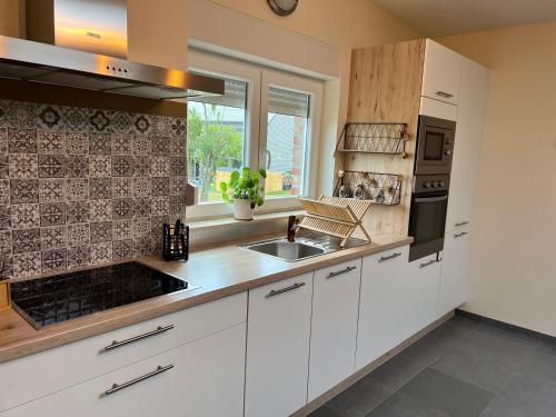 a kitchen with white cabinets and a sink at A l’orée du bois… in Aywaille