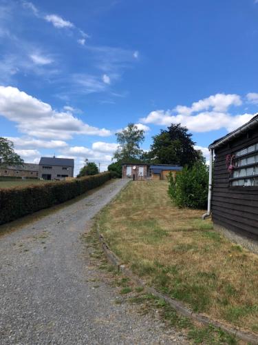 a dirt road next to a house and a building at A l’orée du bois… in Aywaille