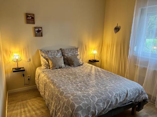 een slaapkamer met een bed met 2 lampen en een raam bij A l’orée du bois… in Aywaille
