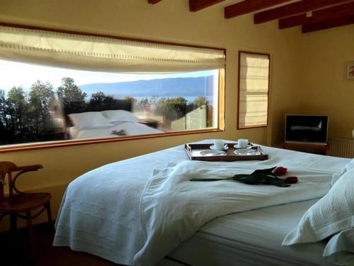 a bedroom with a white bed with a large window at Apart Hotel Sol y Lago in Pucón