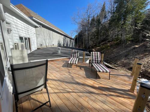 two chairs sitting on a wooden deck next to a house at Auberge Hotel Spa Watel in Sainte-Agathe-des-Monts