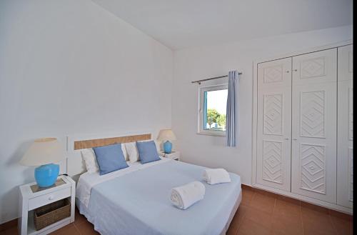 a white bedroom with a large bed and a window at Casa da Prainha - private pool, next to the beach in Alvor