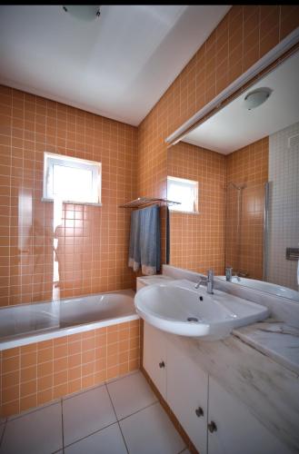 a bathroom with a tub and a sink and a bath tubermott at Casa da Prainha - private pool, next to the beach in Alvor