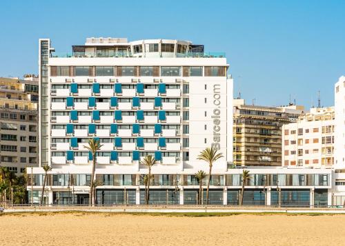 a large white building with palm trees in front of a beach at Barceló Tanger in Tangier