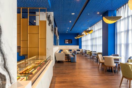 a dining room with blue ceilings and tables and chairs at Barceló Tanger in Tangier