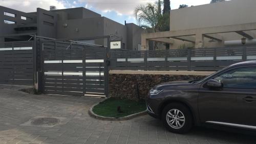 a car parked next to a fence in front of a house at Rom HaTayelet in Arad