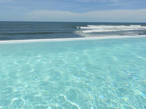 a swimming pool with the ocean in the background at LAOLA SURF CAMP EL SUNZAL in La Libertad